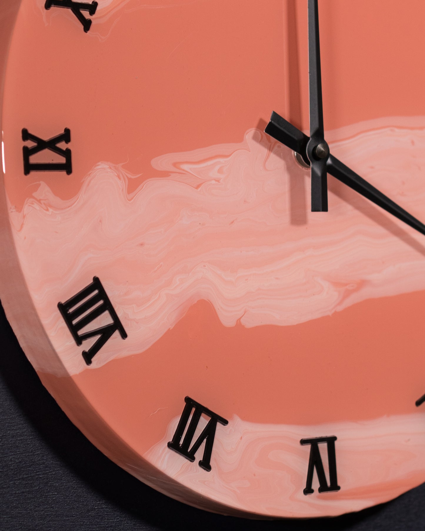 dettaglio in prospettiva di numeri romani neri e lancette di orologio da parete in resina epossidica effetto marmo Rosa